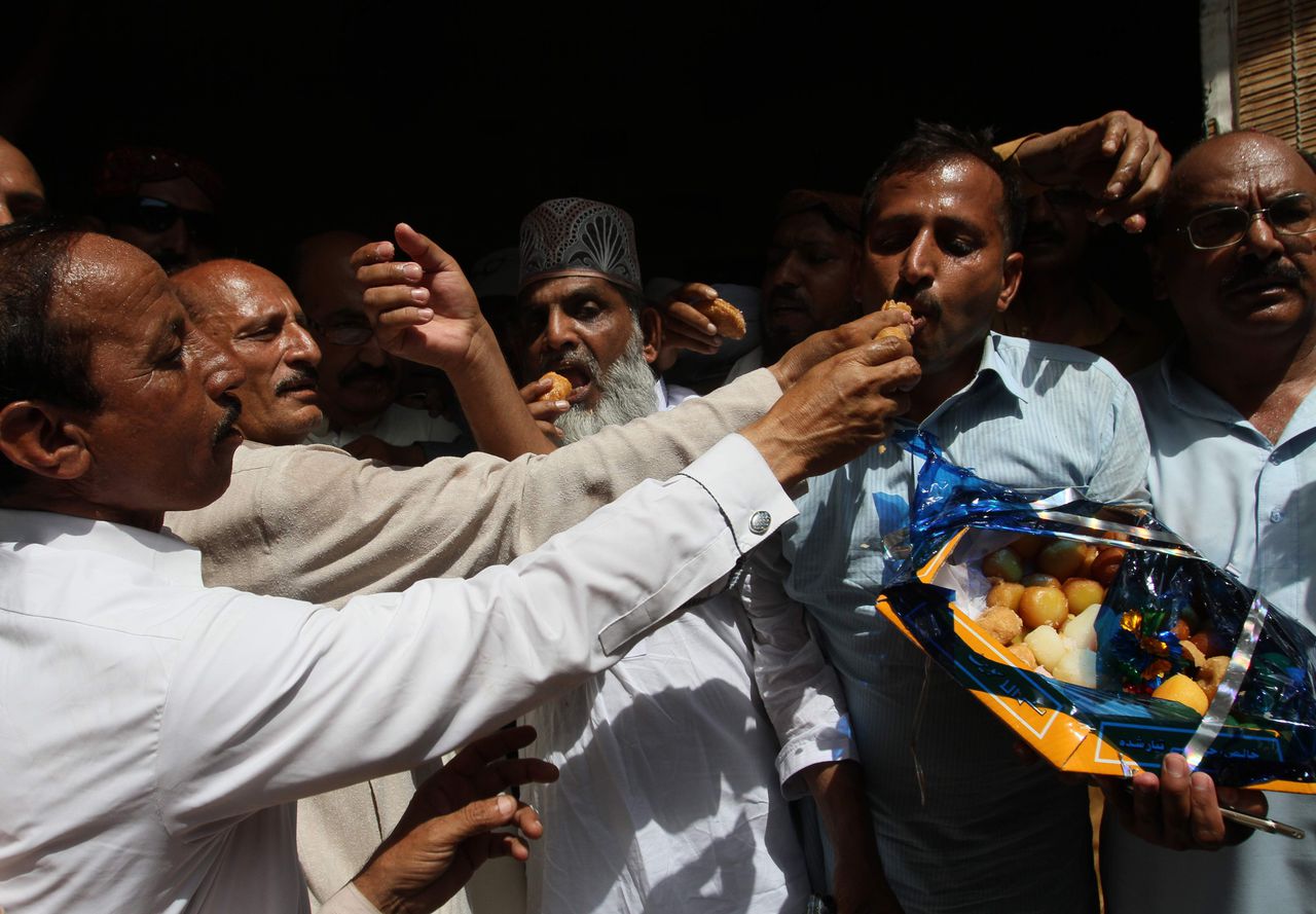 Aanhangers van de voormalig Pakistaanse premier Yousuf Raza Filani vieren de bevrijding van zijn zoon met het uitdelen van lekkernijen.