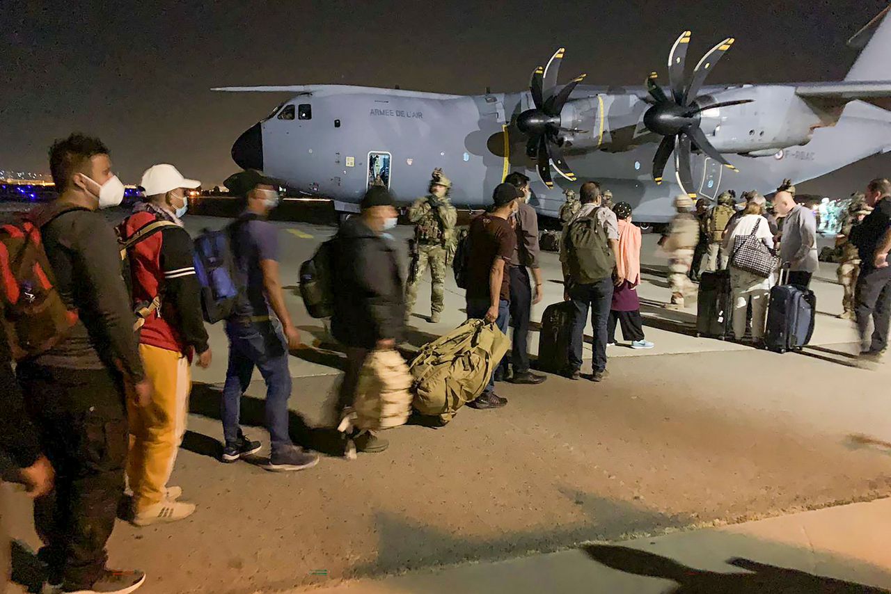 Franse burgers en hun Afghaanse collega's staan disndagochtend in de rij om aan boord te gaan van een Frans militair transportvliegtuig op de luchthaven van Kabul, voor een evacuatievlucht vanuit Afghanistan.