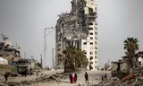Palestinians walk past by Israel destroyed buildings in Gaza City. Photo Haitham Imad / EPA