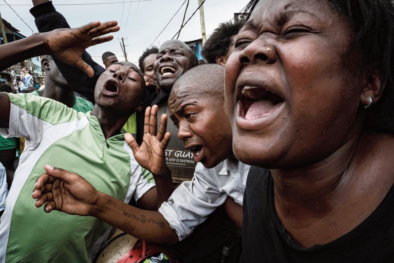 Aanhangers van de oppositie doen alsof ze huilen voor president Kenyatta, tijdens een feest in een sloppenwijk, na de rechterlijke uitspraak.