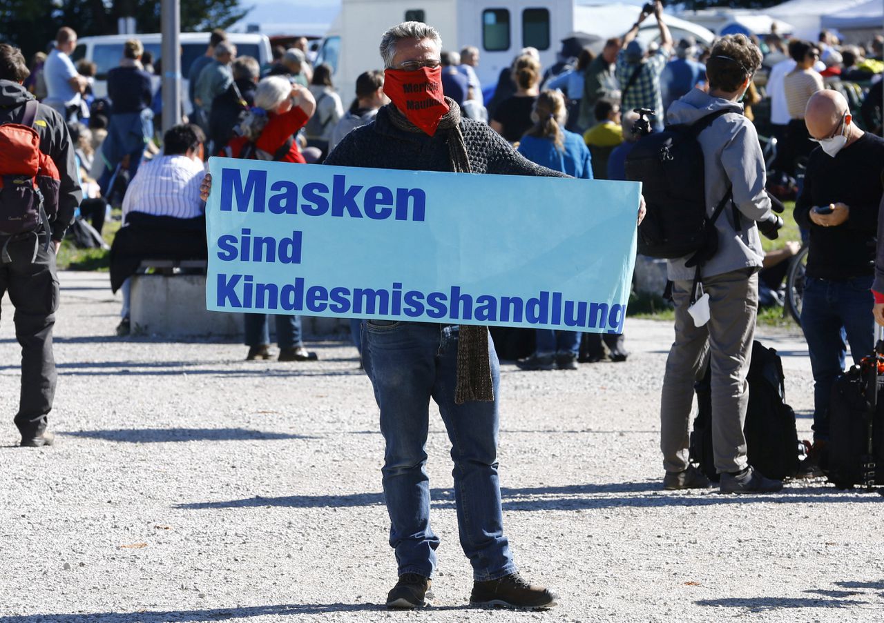 Een man toont een spandoek met de tekst „Mondkapjes zijn kindermishandeling” tijdens een demonstratie tegen coronamaatregelen in de Duitse stad Konstanz.