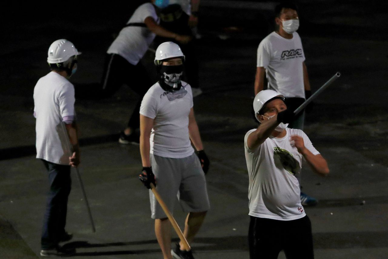 Onbekende, in witte T-shirts geklede mannen vielen in een metrostation in Hongkong pro-democratische demonstranten aan met stokken.