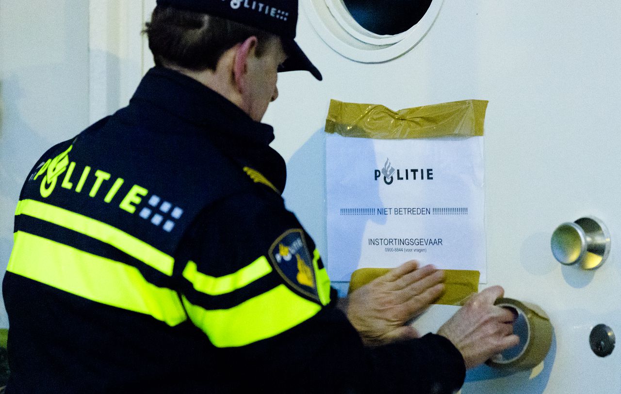 De politie aan het werk in Tilburg. Deze agent plakt een mededeling aan een huis in de Philips Vingboonsstraat.