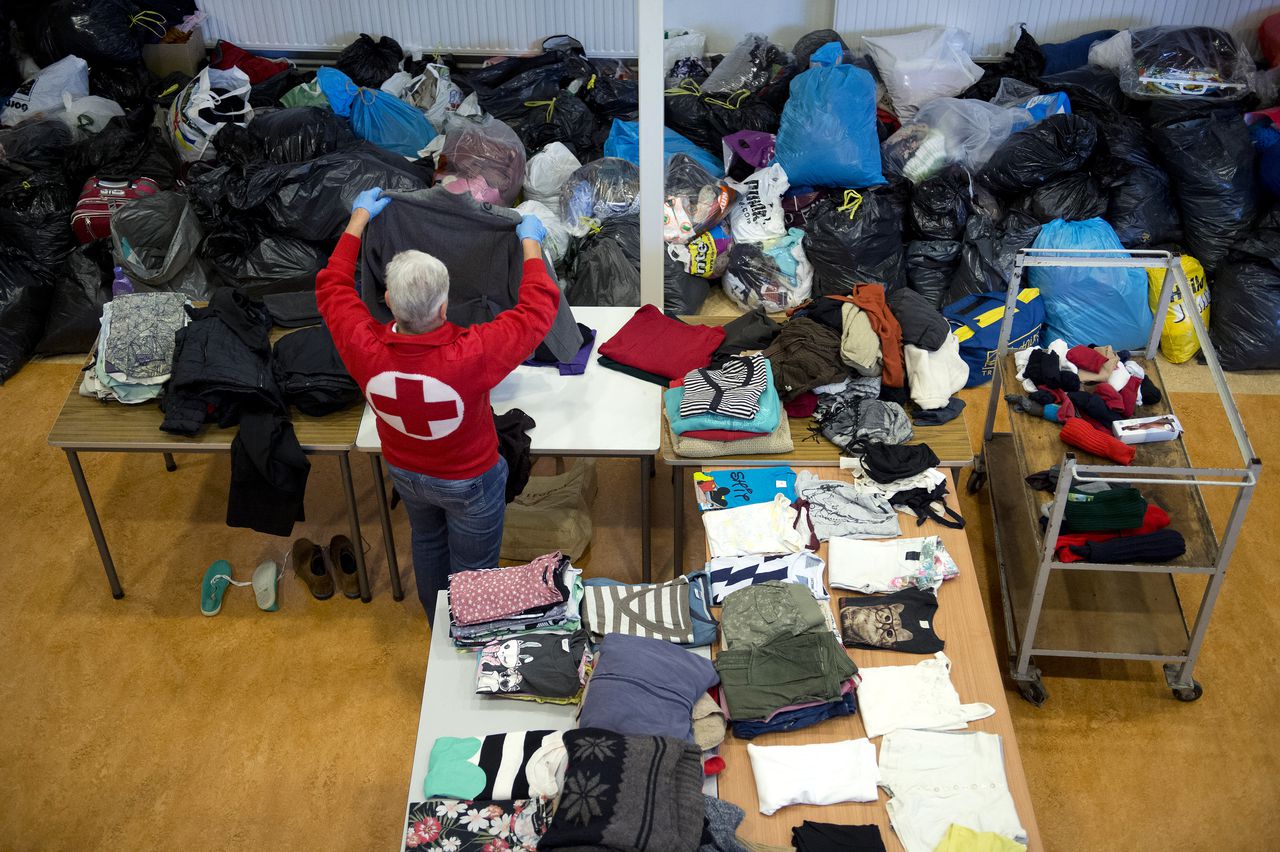 Een werknemer van het Rode Kruis sorteert kleding in de Van Horne Kazerne in Weert.