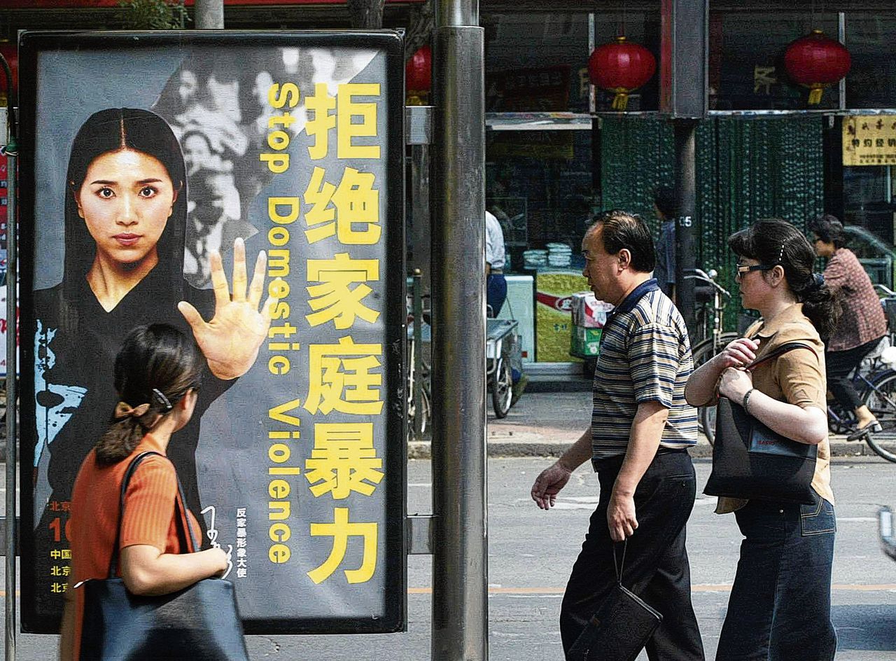 Voorbijgangers lopen langs een advertentie tegen huiselijk geweld in Beijing in 2002, het jaar dat een begin werd gemaakt met wettelijke maatregelen tegen huiselijk geweld.