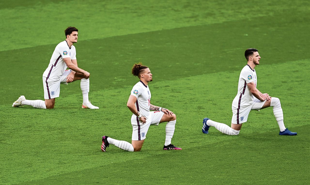 Spelers van het Engelse elftal knielen voor de aftrap.
