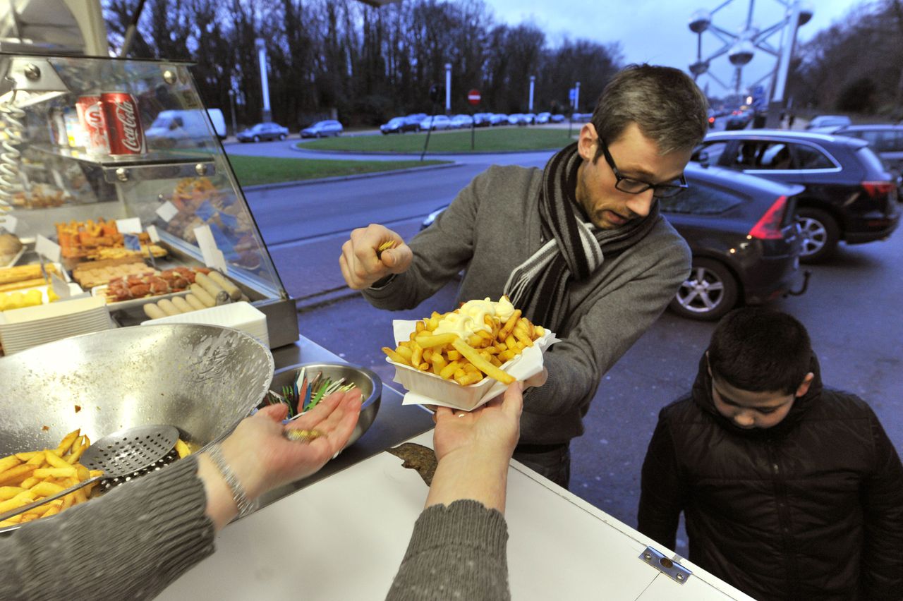 TO GO WITH : "Belgium's beloved chip stall fights to survive" by Laurent Thomet Josiane Devlaeminck serves Belgian fries to customers at the Atomium "fritkot", the Flemish word for fries stand, in Brussels on Feburary 7, 2011. Fewer than 1,500 fritkots are scattered around the country today, after thousands were driven out in the past two decades by stringent European health rules and aesthetics-conscious municipalities which see the greasy stalls as eyesores. AFP PHOTO/GEORGES GOBET