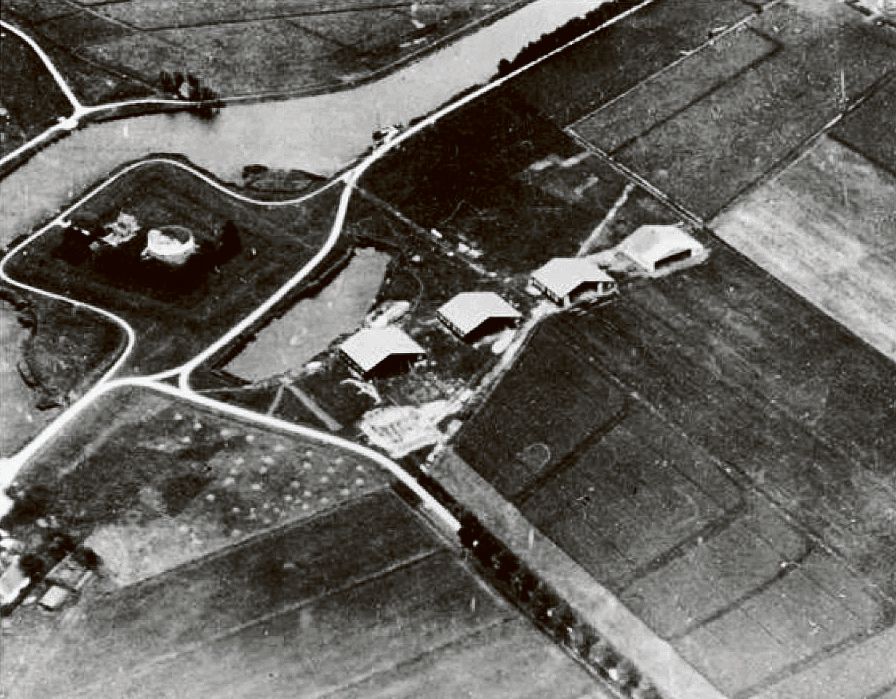 Vliegkamp Schiphol in 1916. Vier loodsen en 76 hectare weiland naast Fort Schiphol, onderdeel van de Stelling van Amsterdam. Op 19 september 1916 landde het eerste toestel, een militaire Farman tweedekker.