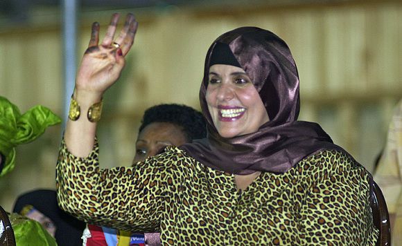 Caption: FILE - In this Monday, Sept. 1, 2003 file photo, showing Safiya Gadhafi, the wife of Libyan leader Moammar Gadhafi, waves at Libyan soldiers during a military parade at Tripoli's main square. Ousted Libyan leader Moammar Gadhafi's wife and other relatives fled to Algeria Monday, the Algerian foreign ministry said, declaring that Gadhafi's wife, daughter, two of his sons and their children entered the neighboring country on Monday. It did not say whether Moammar Gadhafi himself was with the family group. (AP Photo/Amr Nabil, File)