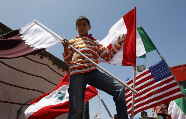 A Libyan boy holds Qatar, Canada, Italy, Lebanon and US flags before Friday prayers near the court house in Benghazi April 15, 2011. A fresh hail of government rockets crashed into Misrata on Friday after Western allies denounced a "medieval siege" of the city and vowed to keep bombing Muammar Gaddafi's forces until he stepped down. REUTERS/Amr Abdallah Dalsh (LIBYA - Tags: CIVIL UNREST POLITICS)