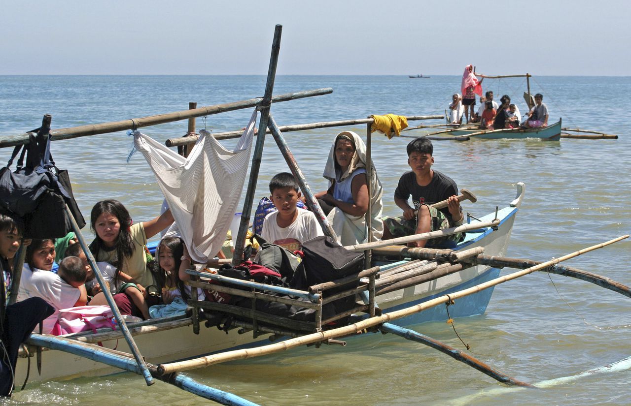 Bewoners van Kauswagan ontvluchtten in bangka?s, traditionele Filippijnse bootjes, de gewelddadigheden in hun dorp in augustus vorig jaar. (Foto Reuters) Residents ride a boat with their belongings as they flee Kauswagan town, Lanao del Norte southern Philippines August 18, 2008. The Philippines ordered troops to clear Muslim guerrillas out of several towns on the southern island of Mindanao on Monday after they attacked soldiers, burnt houses and forced hundreds of people to flee. REUTERS/Stringer (PHILIPPINES)