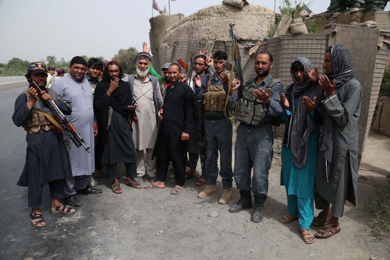 Vermoedelijk strijders van de Talibaan poseren zondag 17 juni met de Afghaanse politie in Jalalabad, tijdens de wapenstilstand.