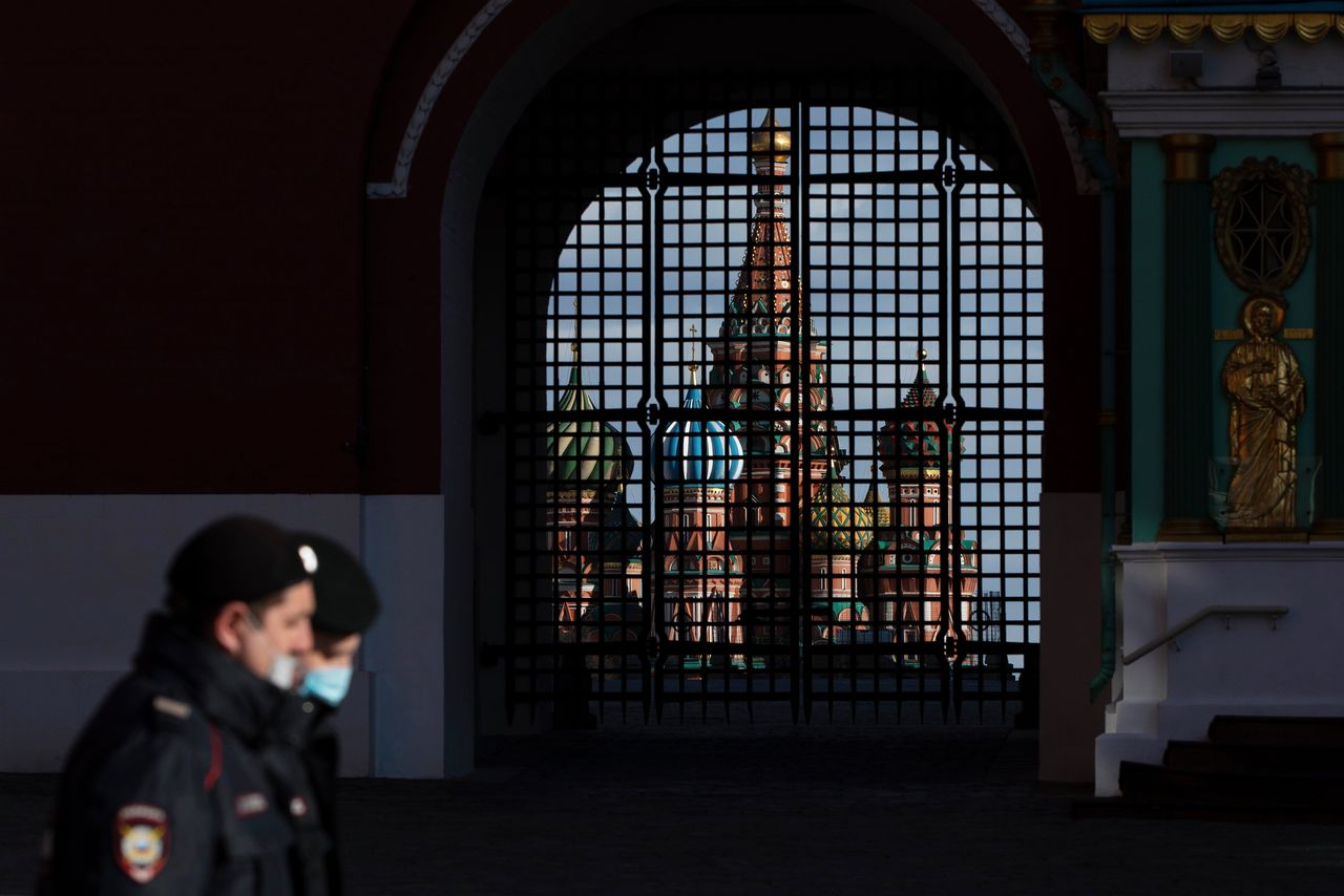 Politieagenten met mondkapjes voor de Opstandingspoort bij de Basiliuskathedraal op het Rode Plein in Moskou.