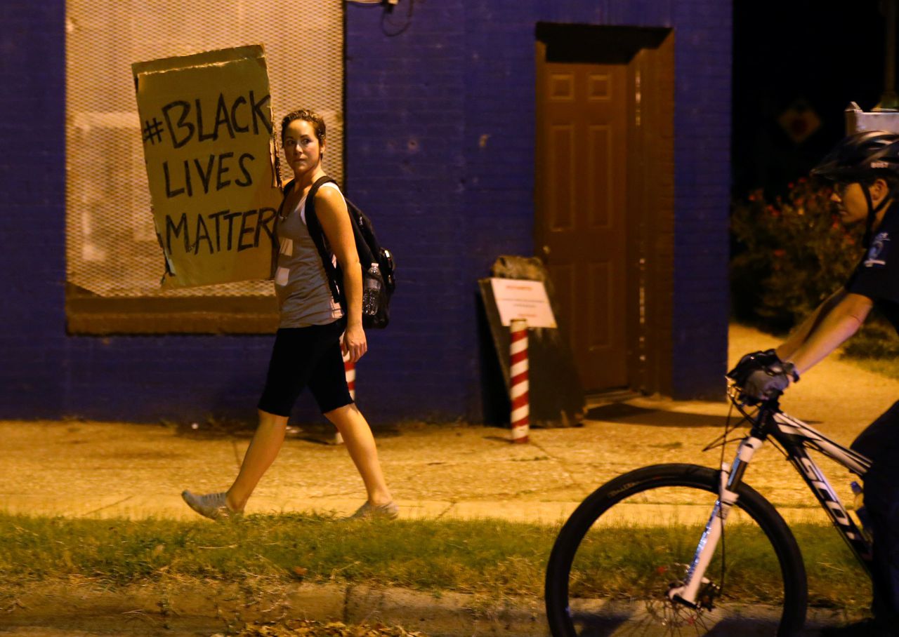 Een demonstrant loopt over straat in Charlotte met een protestbord.