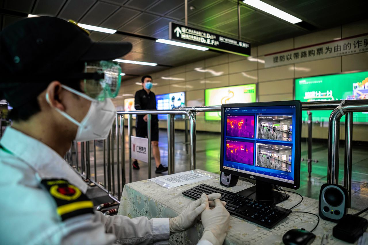 Een Chinese beveiliger bekijkt warmtecamera’s die koorts meten van metroreizigers om patiënten met het coronavirus te herkennen. De camera’s maken gebruik van 5G-technologie.