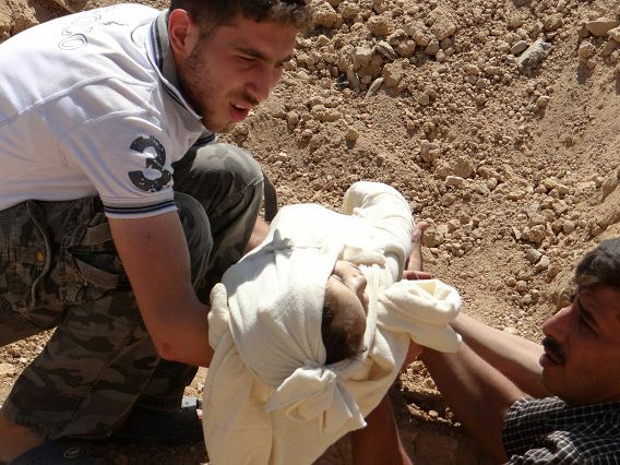 Een kind wordt in een massagraf gelegd, volgend op een vermeende aanval met gifgas vlak bij Damascus.