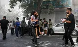 Een man in Teheran met een gewond meisje op zondag, na een van de aanvallen van Israël.  Foto Morteza Zangene/AP 