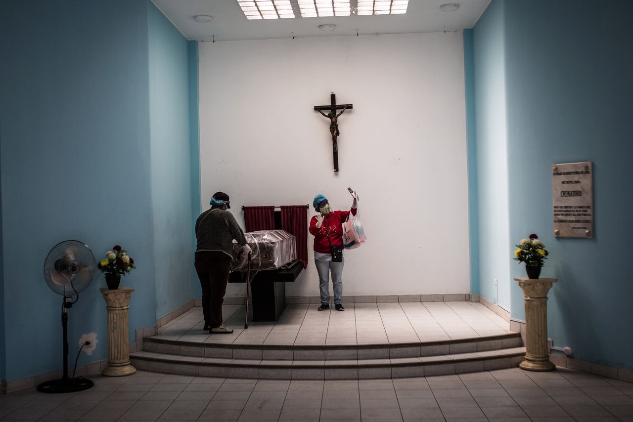 Een Peruaanse vrouw neemt in een crematorium in Lima afscheid van haar aan Covid-19 overleden man, terwijl haar dochter het tafereel met een selfie vastlegt. Vanwege de uitbraak van het virus mogen nog slechts twee personen tegelijkertijd naar binnen.