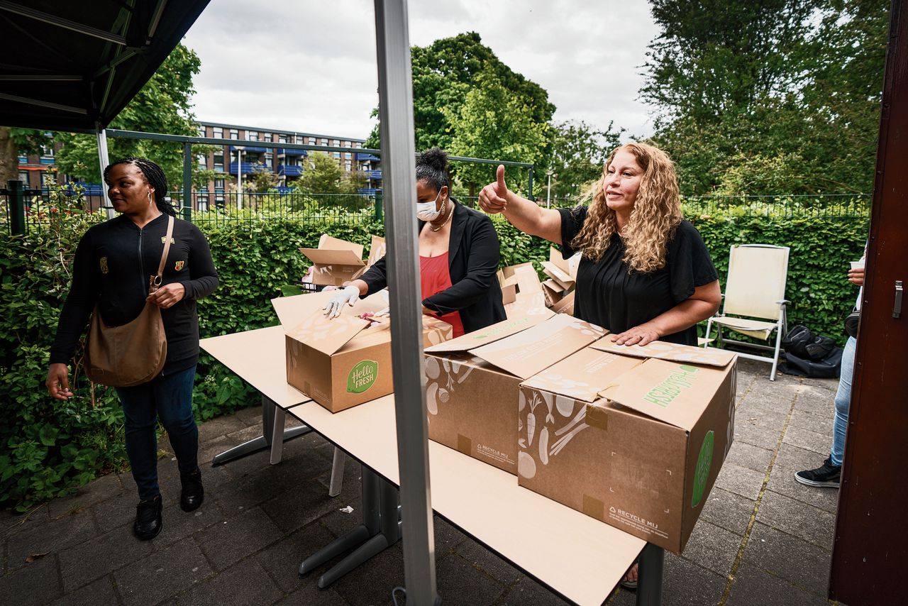 Maureen Hubbard (met mondkapje) en Leila Azzam van de stichting Carabic delen voedselpakketten uit in een buurtcentrum in Amsterdam Zuidoost.
