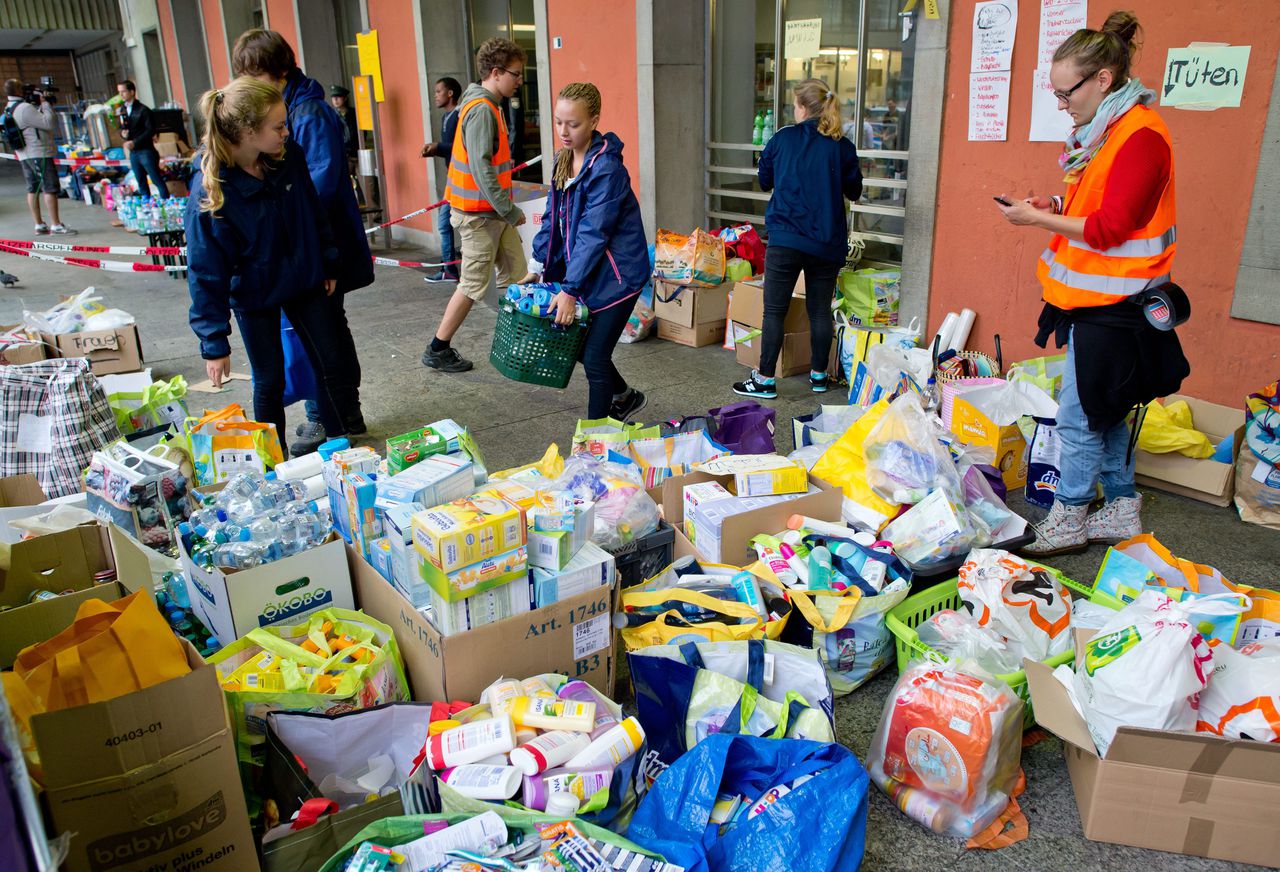 Vrijwilligers staan klaar met gedoneerde spullen op het centrale station van München.