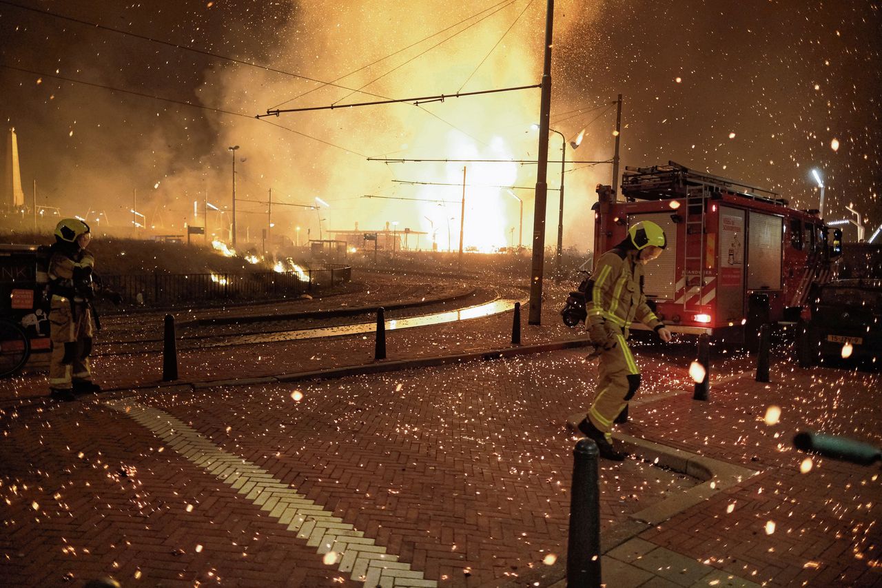 Brandweerlieden proberen in de Scheveningse Zeeruststraat de gevolgen van het vreugdevuur te bestrijden.