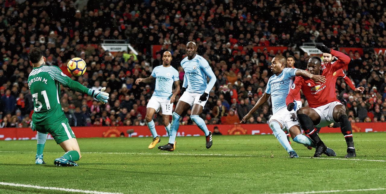 Een schot van Romelu Lukaku (rechts) wordt gekeerd door keeper Ederson (links) van Manchester City.