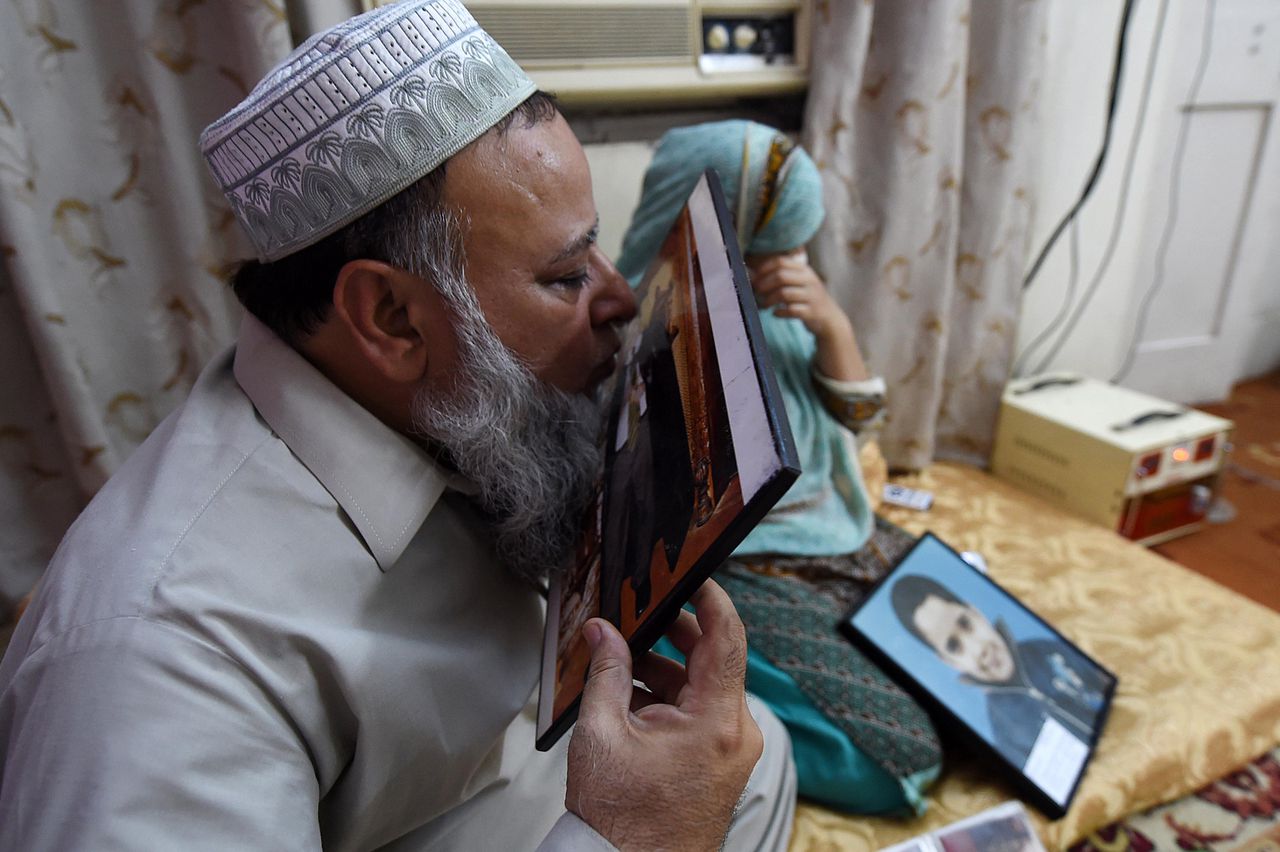 De vader van de omgekomen scholier Malik Usam Tahir Awan kust zijn foto in Peshawar, Pakistan.
