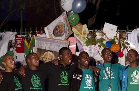 Een groep studenten zingt een verjaardagsliedje voor Mandela buiten bij het ziekenhuis in Pretoria waar de oud-president verblijft. Mandela is vandaag 95 jaar geworden en tegen de verwachtingen in gaat zijn gezondheid gestaag vooruit.