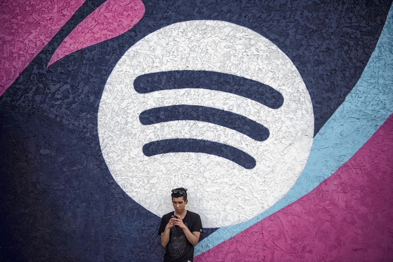 Een bezoeker van het festival SXSW in Austin (VS) leunt tegen een muur met het logo van audiostreamingdienst Spotify.
