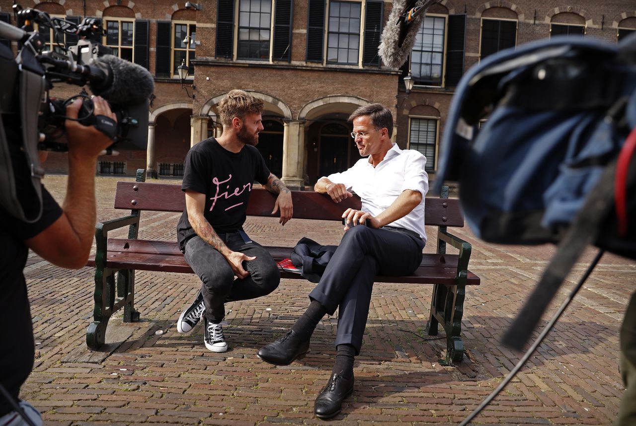 Tim Hofman interviewt Mark Rutte (VVD) op een bankje op het Binnenhof in Den Haag. Foto uit augustus vorig jaar.