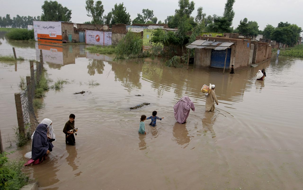 Inwoners van een Pakistaans dorp vlakbij Peshawar waden zich door het water.