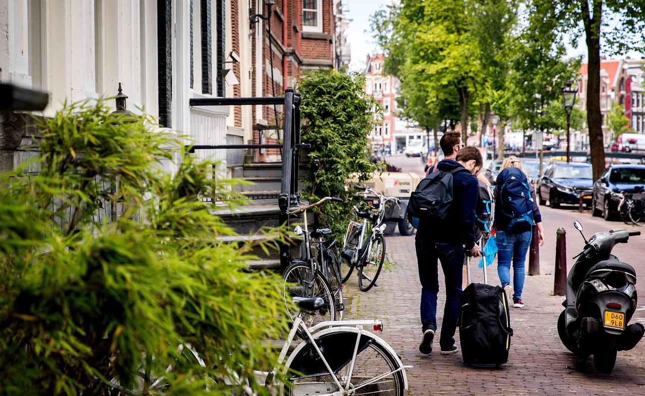 Toeristen met rolkoffers in Amsterdam. Airbnb zegt nu toe de overlast van toeristen die via hun website een woning in grote steden huren tegen te gaan.