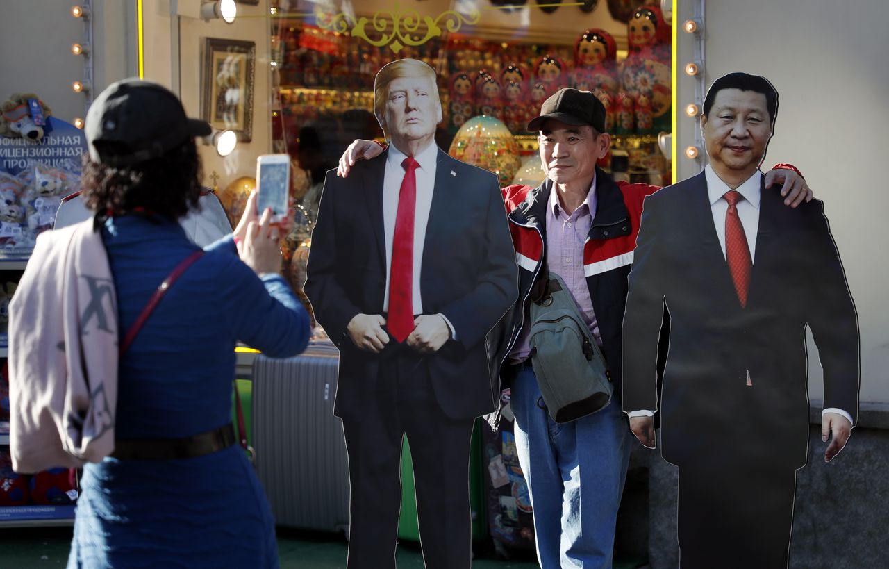 Chinese toeristen gaan in het centrum van Moskou op de foto met kartonnen poppen van Donald Trump en Xi Jinping.