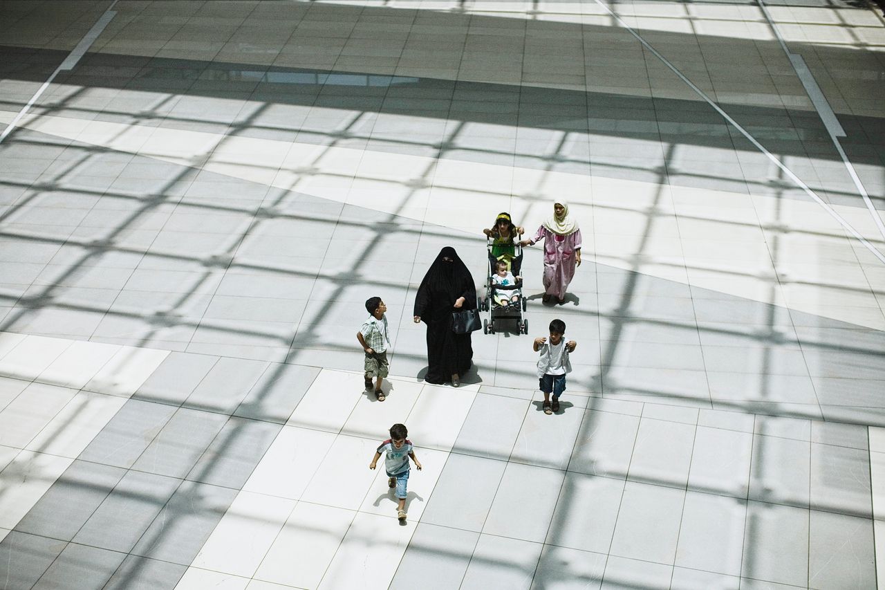 Een vrouw uit Koeweit wordt samen met haar kinderen bijgestaan door hun huishoudelijke hulp in een winkelcentrum in Koeweit Stad.
