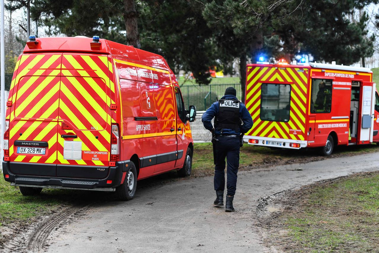Een agent loopt langs brandweerauto's in het park in Villejuif, waar een man doodgeschoten werd door de politie nadat hij instak op voorbijgangers.