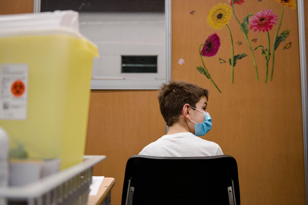 Een Canadese jongen zit in de wachtruimte nadat hij het Pfizer-vaccin heeft ontvangen.