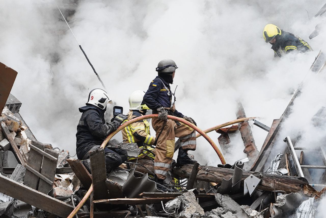 Oekraïense brandweermannen werken tussen de puinhopen na een Russische raketaanval op het centrum van Charkov
