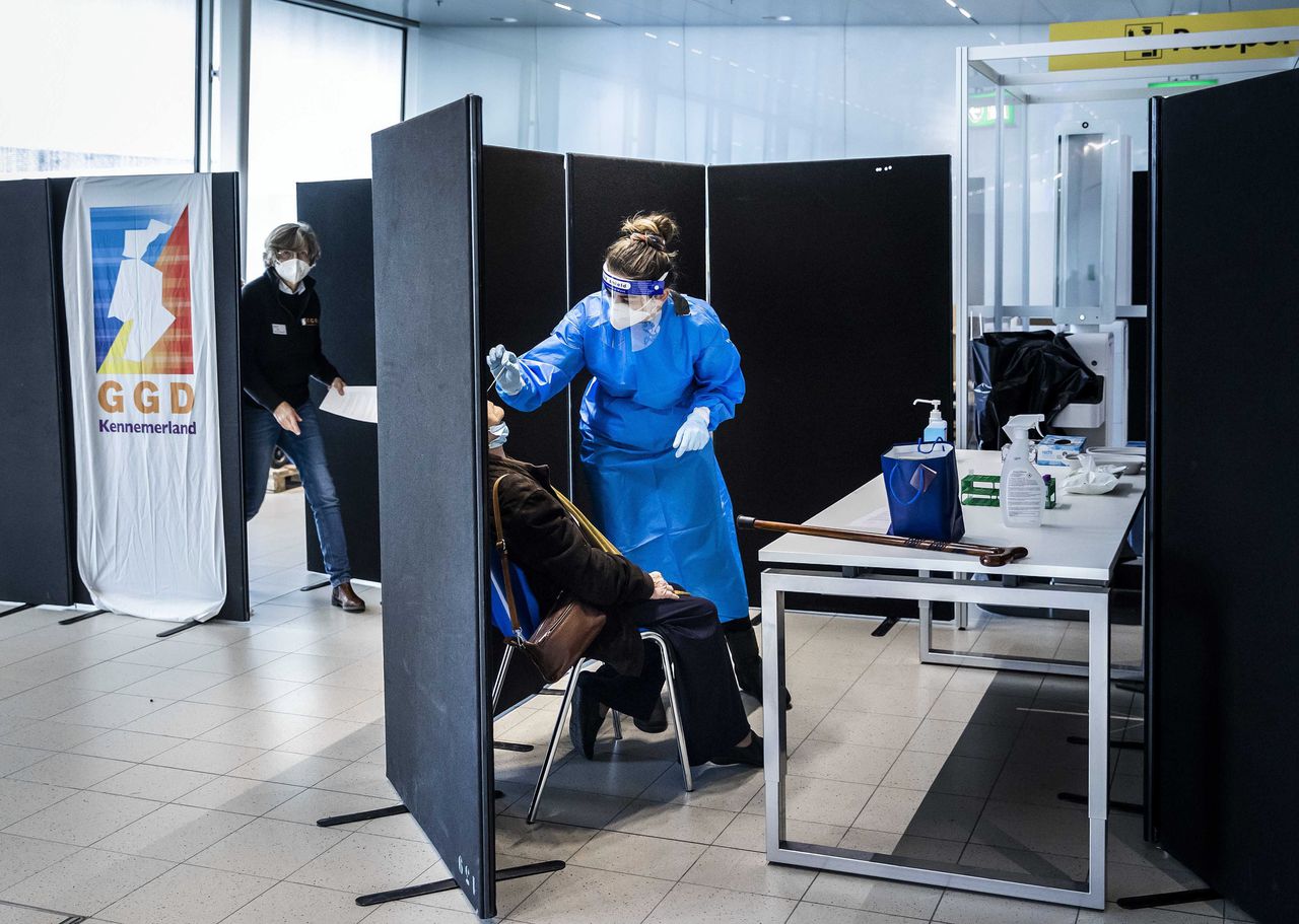 Reizigers uit Zuid-Afrika laten zich bij aankomst op Schiphol testen op het coronavirus in een speciaal daarvoor ingerichte teststraat.