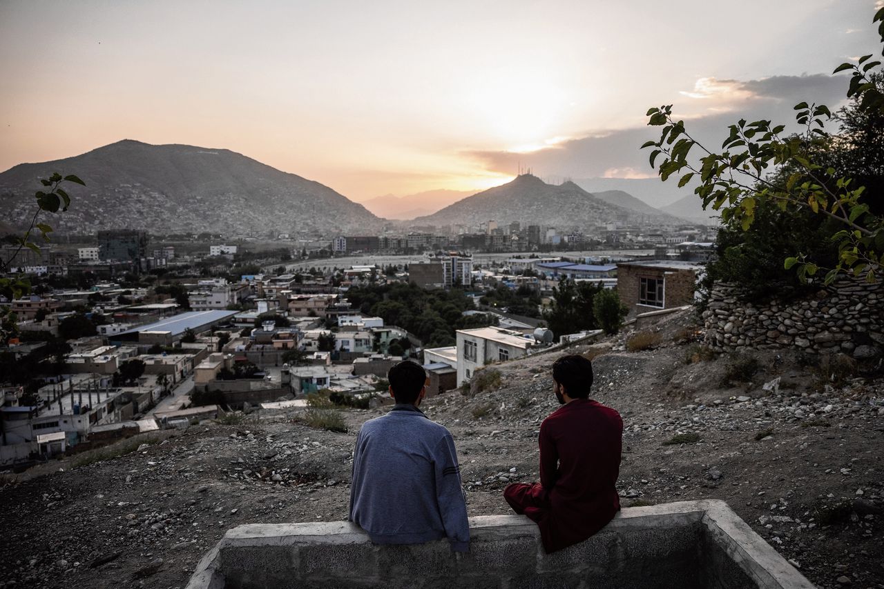 Twee vrienden kijken vanuit de heuvels naar de zonsondergang in de Afghaanse hoofdstad Kabul.