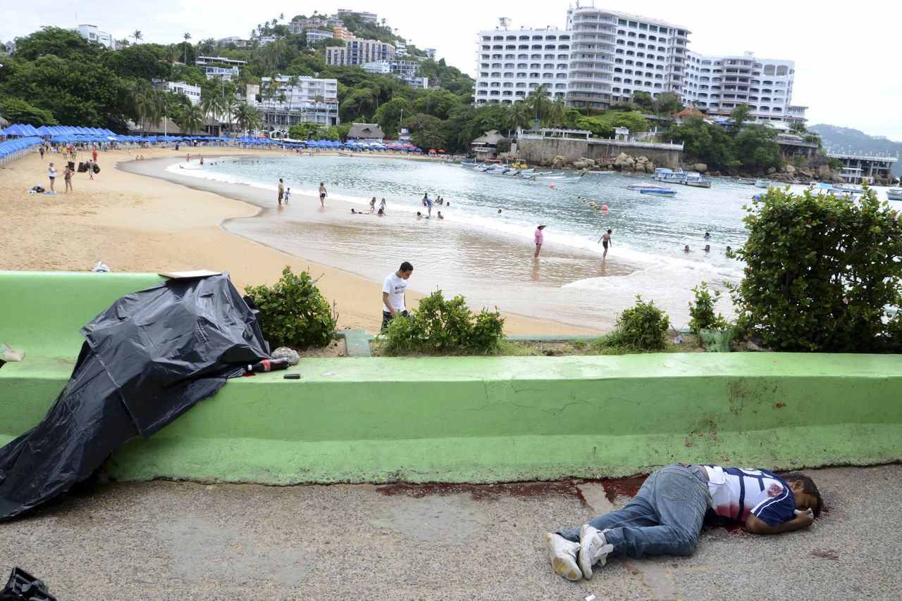 ADVANCE FOR RELEASE SUNDAY, DEC. 11, AND THEREAFTER - EDS. NOTE GRAPHIC CONTENT - FILE - In this Aug. 16, 2011 file photo, the bodies of two men shot dead next to the Caleta beach, lie, one of them covered, in the Pacific resort city of Acapulco, Mexico. The city of Acapulco has been hit by violence as drug gangs continue to battle for control of the region. Five years after President Felipe Calderon launched his assault on organized crime, About 45,000 troops have been deployed, plus several thousand more from the Navy infantry, or marines. More than 45,000 people have been killed by several counts, though the government stopped giving figures on drug war dead when they hit nearly 35,000 a year ago. Still, the flow of drugs continues unabated into the U.S. while arms and money flow into Mexico. (AP Photo/Bernandino Hernandez, File)