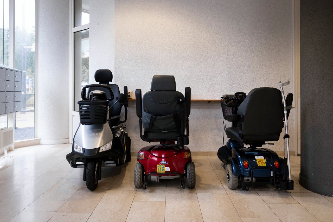 De scootmobielen staan in de gang terwijl ouderen bingo spelen in een verzorgingstehuis in Rotterdam.