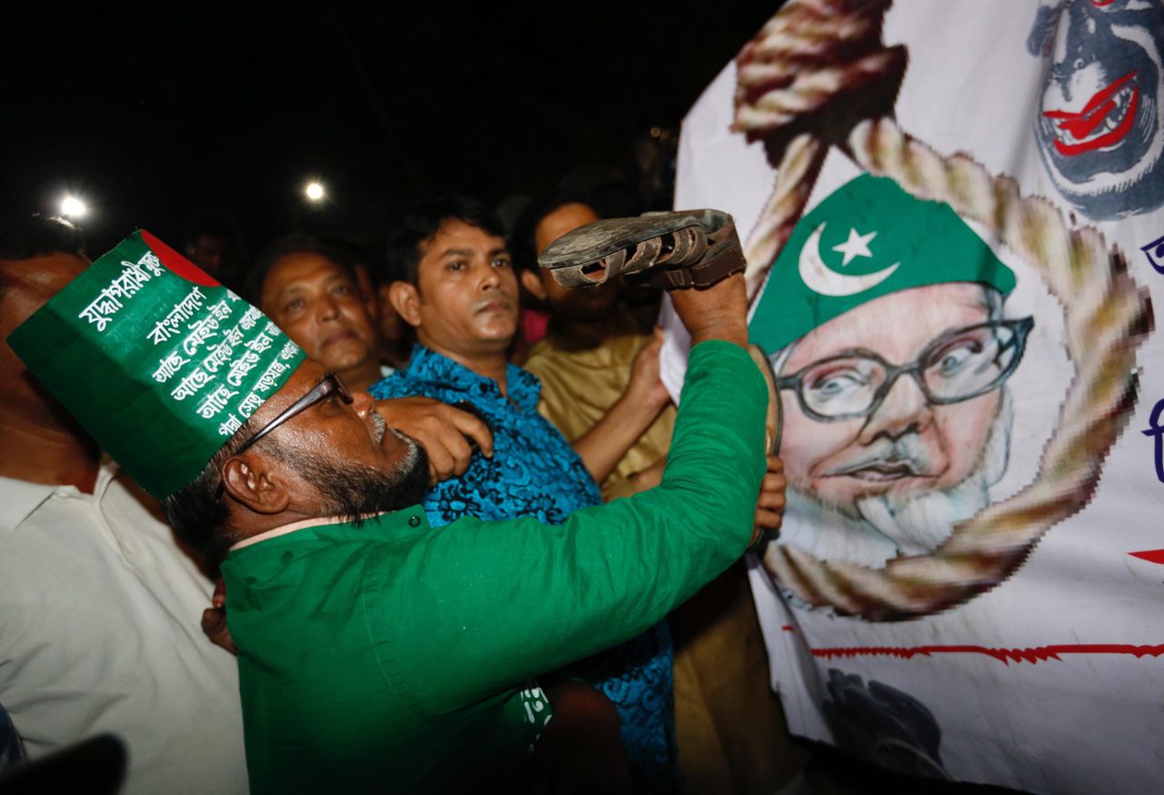 Een Bengaalse man viert de dood van Nizami door een schoen tegen zijn portret aan te gooien.