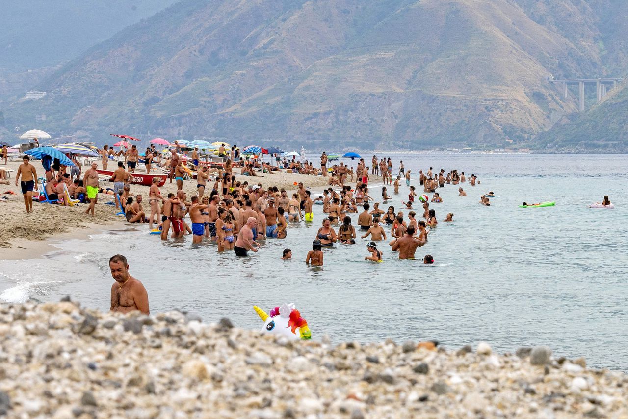 Strandgangers zoeken op Sicilië verkoeling in de zee bij Messina.