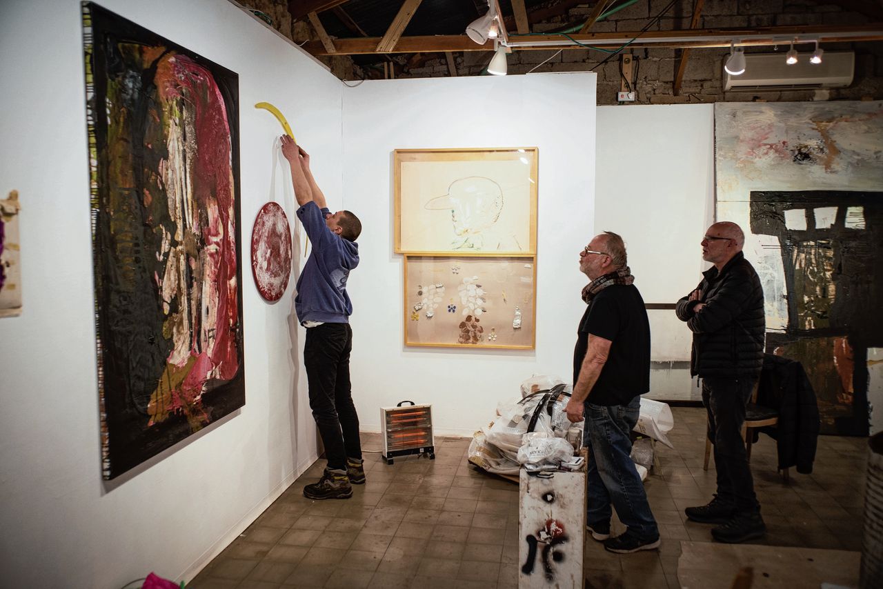 Medewerkers van galerie Barbur hangen kunst op voor de nieuwe tentoonstelling.