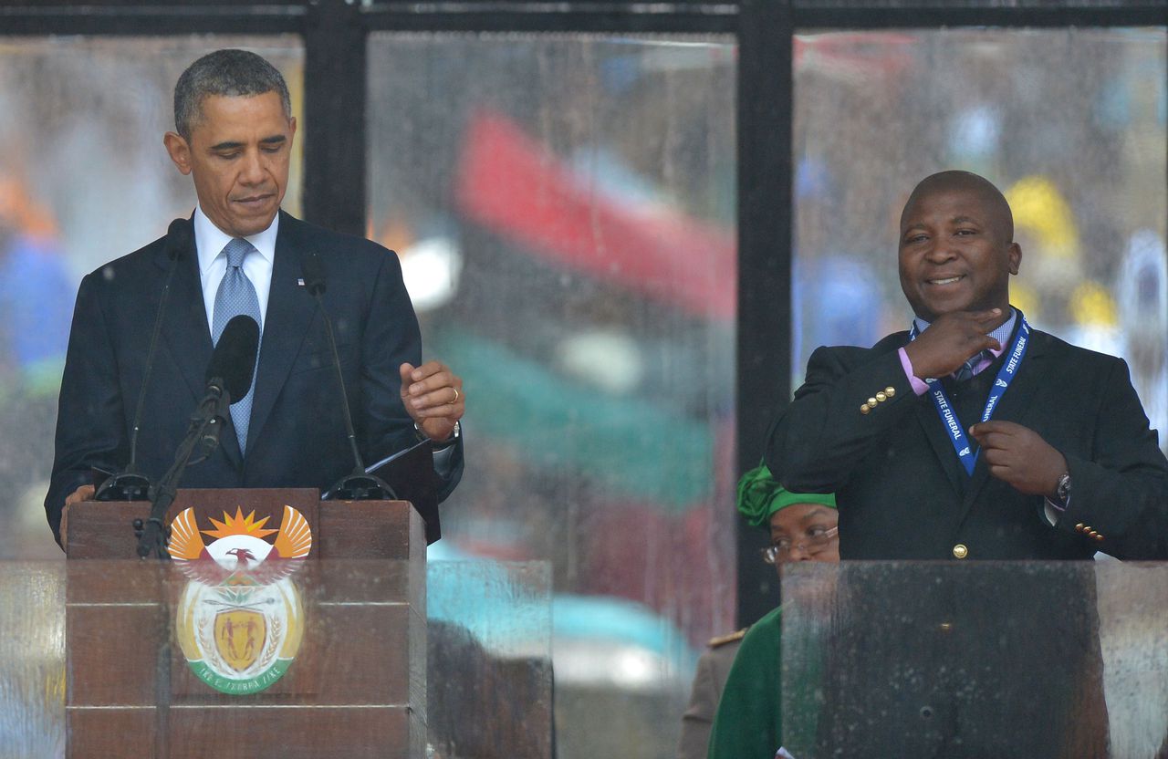 Thamsanqa Jantjie flankeert Barack Obama terwijl hij opzichtig miskleunt bij het vertalen van de geroemde speech van de Amerikaanse president. AFP / Brendan Smialowski