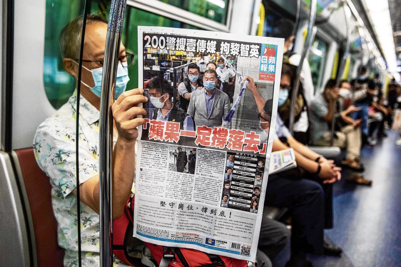 Een forens in Hongkong leest de Apple Daily, daags na de arrestatie van Jimmy Lai, de uitgever van de krant, vorige zomer.