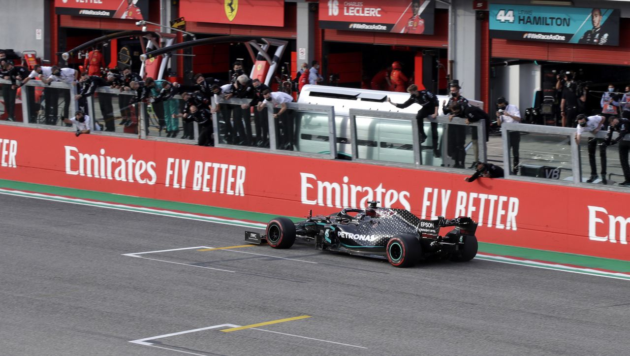 Lewis Hamilton wordt bij de finish toegejuicht door de pitcrew van Mercedes.