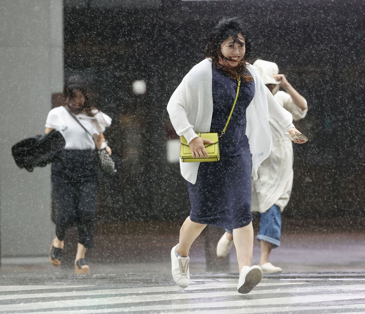 Inwoners van het zuidelijke hoofdeiland van Japan lopen door regen en wind. Van zondag tot woensdag blijft de supertyfoon aan land.