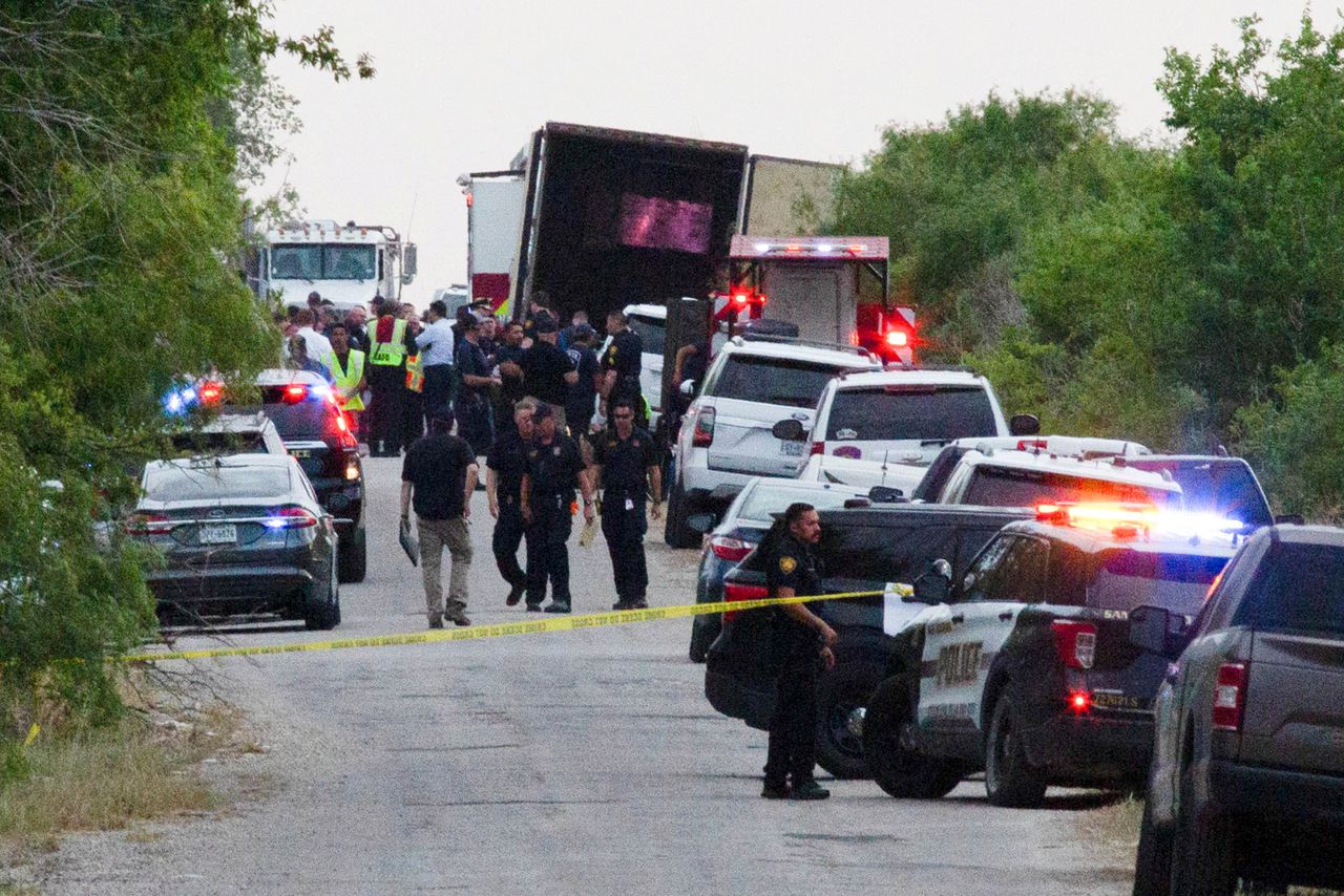Agenten lopen bij de plek aan de rand van de Amerikaanse stad San Antonio, in de staat Texas, waar tientallen mensen maandag dood zijn aangetroffen in een vrachtwagen.