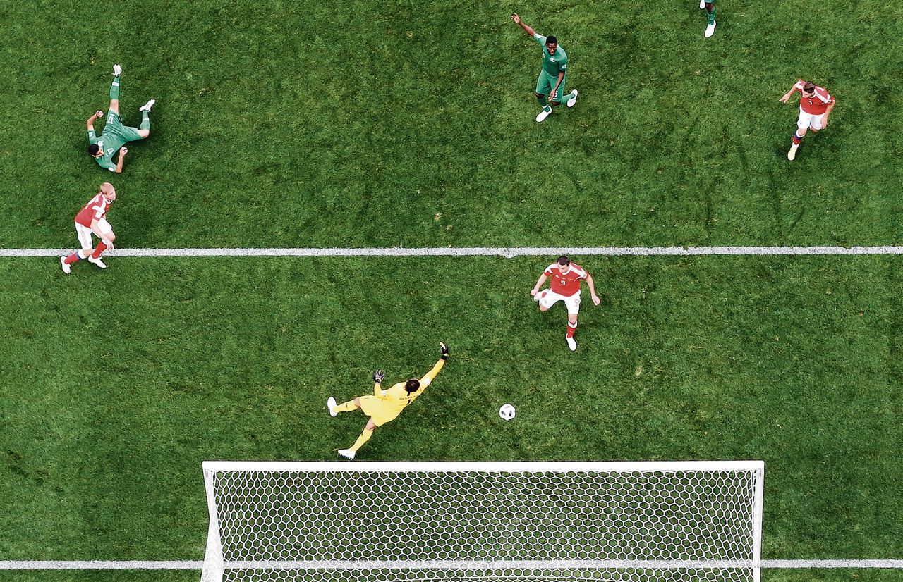 De Rus Joeri Gazinski (links, in rood shirt) maakt in de openingswedstrijd tegen Saoedi-Arabië het eerste doelpunt van het WK 2018.
